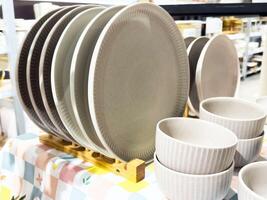 Set of ceramic plates and bowls on wooden stand in store display photo