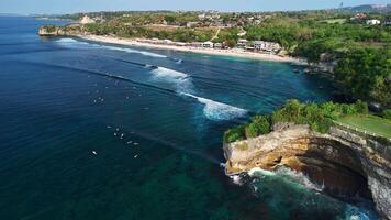 Aerial view of beach with scenic rock and surfers in ocean in Balangan beach, Bali video