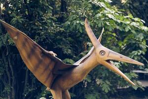 Dinosaur park in an open space. A dinosaur garden with predators and herbivores of the Jurassic period. A pterodactyl with space to copy photo
