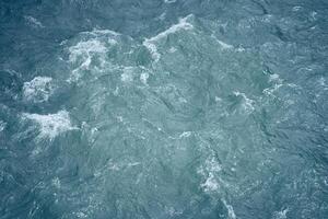 Beautiful background with blue water and a place to copy. Close-up of raging waters. Ripples and waves on the water. photo