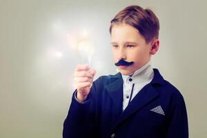 Portrait of a humorous vintage scientist. A child with a false mustache and a light bulb. Success, idea and education. photo