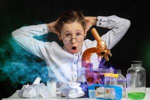 A boy scientist researcher with a microscope conducts experiments in the laboratory. Surprise in the laboratory. Science and education. photo