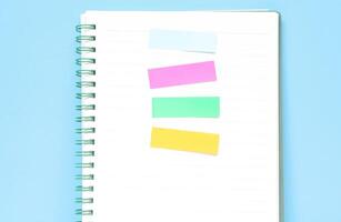Four colored markers in a notebook on a wooden table. Colorful post paper notes or bookmarks on gray background. Journaling and office desk concept photo