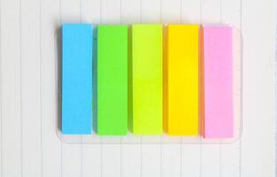 Five colored bookmarks for books on a wooden table. Colorful post paper notes or bookmarks on gray background. Journaling and office desk concept photo
