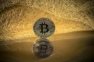 Bitcoin with mirror image in front of a tile made of gold threads photo