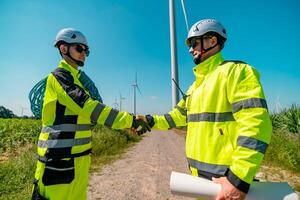 Engineers shake hands at a wind farm after a successful project collaboration in bright daylight photo