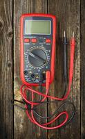 Digital multimeter on a wooden table. A device for measuring electrical quantities. View from above. photo