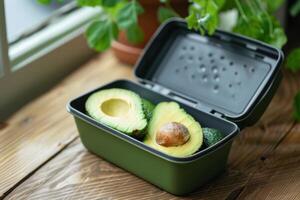 Avocados in container resting on wooden table near window with herbs growing photo