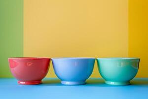 Three empty colorful bowls sitting on blue table with yellow and green background photo