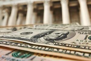 Pile of one hundred dollar bills lying on a table with government building in background photo