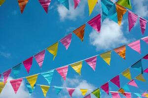 Colorful triangle flags hanging on string on blue sky background with clouds photo
