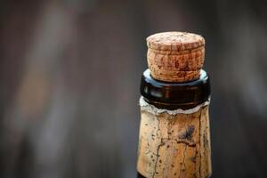 Old sparkling wine bottle with cork closeup on dark background photo