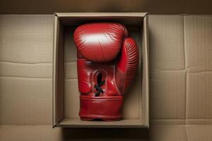 Red boxing glove resting inside open cardboard box photo