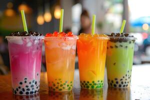 Four colorful bubble teas with boba pearls and popping boba resting on cafe counter photo