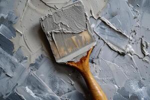 Brush applying plaster on wall creating textured surface photo
