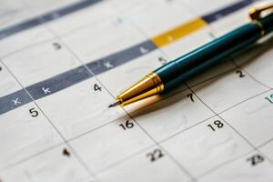 Pen pointing to date on calendar page, planning and scheduling concept photo