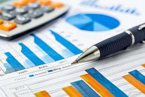 Pen and calculator resting on financial charts displaying business success photo