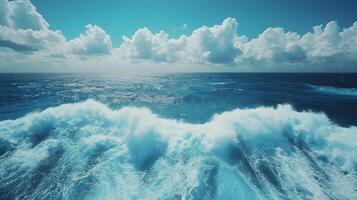 Ocean wake pattern stretches behind cruise ship in aerial view. Deep blue sea meets bright sky with white clouds, while turquoise foam trails create dynamic water movement on sunny day. trails photo