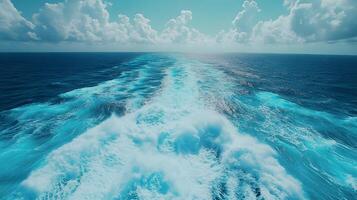 Ocean wake pattern stretches behind cruise ship in aerial view. Deep blue sea meets bright sky with white clouds, while turquoise foam trails create dynamic water movement on sunny day. movement photo