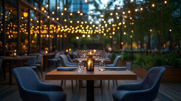 Outdoor restaurant terrace features wooden dining tables and modern grey chairs, illuminated by string lights. Deck flooring and candlelight create warm evening ambiance for cozy patio patio photo