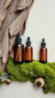 Three bottles of essential oils sit on a mossy branch photo