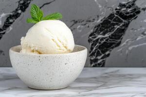 A scoop of vanilla ice cream in a small bowl, garnished with mint photo