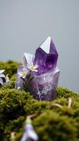Amethyst crystal on moss with flowers photo