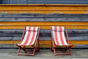 Two empty red and white striped deckchairs in front of colorful wooden wall photo