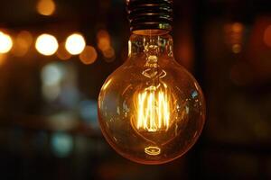 Bright light bulb shining in a dark room with blurred lights in background photo