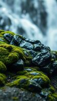 A moss covered rock in front of a waterfall photo