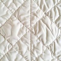 Beige quilted fabric texture creating diamond pattern with visible stitching photo