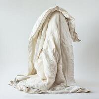 White quilt draped over invisible object creating abstract shape on white background photo