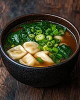 Delicious dumplings in a savory broth with spinach and green onions photo