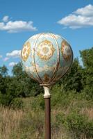 Rustic globe on rusty pole in field photo