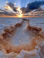 Sunset over a salt flat with a channel of water photo