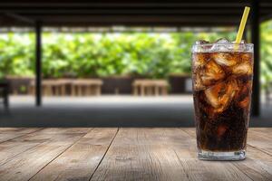 Refreshing cola drink with ice in a glass on a wooden table photo