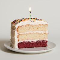 Delicious three layered birthday cake with sprinkles and a lit candle photo