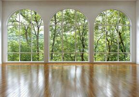 Empty room with large arched windows overlooking a lush green forest photo