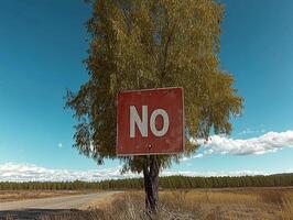 Red sign with the word no on a tree in a field photo