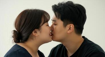 Tender moment between asian couple sharing intimate kiss in minimalistic setting photo