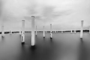 Upright. Pillars in the water in black and white. Minimalist fine art concept. photo