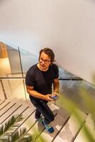 A businessman walking up the stairs using his smartphone, vertical photo with copy space