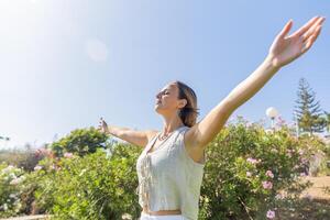 A woman is standing in a field of flowers, with her arms, Concept of peace and happiness. photo