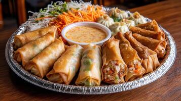 beautifully arranged platter of spring rolls and dumplings with sauce photo