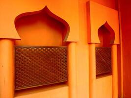 Islamic building architectural background. Orange building has arched windows and a decorative archway. The building is orange and has a warm, inviting feel photo