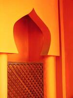 Small archway with a wooden lattice on the inside. The archway is orange and the lattice is brown photo