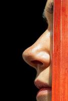 Close up profile of a womans face partially obscured by a red object photo