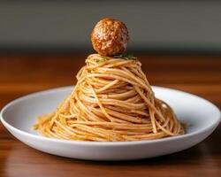 Single meatball on top of a spaghetti and tomato sauce mound photo