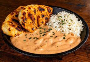 Delicious butter chicken with naan and rice photo