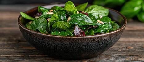 Close up of a delicious spinach salad with sunflower seeds in a dark brown bowl photo